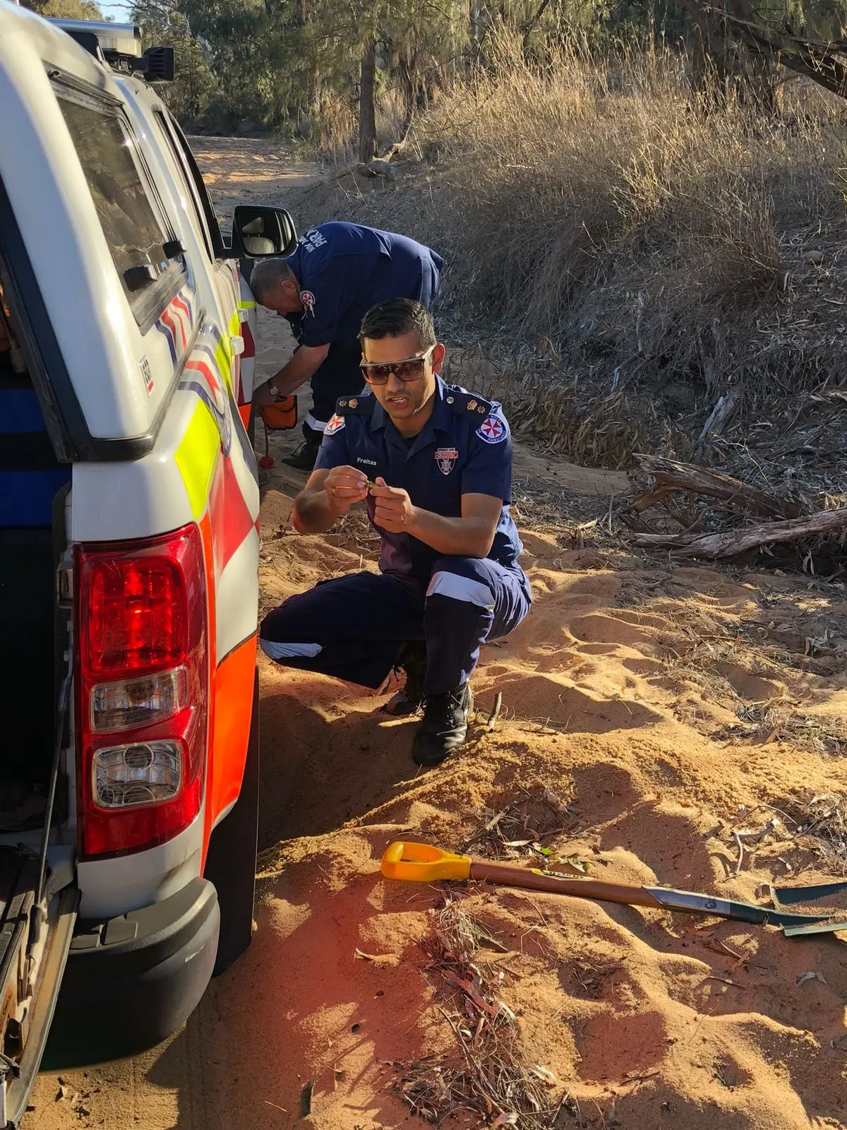Eddie Freitas in paramedic uniform beside an ambulance on a bush track